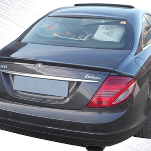 May include: A dark gray Mercedes-Benz CL 600 coupe with a Lorinser rear spoiler. The car has a sunroof and a rear window with a white pillow inside.