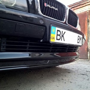 K&ouml;nnte beinhalten: Schwarze BMW Limousine mit schwarzem Frontsto&szlig;f&auml;nger und einem Nummernschild mit der Aufschrift "BK BM" und einem ukrainischen Flaggenaufkleber. Das Auto hat ein "ALPINA" Emblem auf dem K&uuml;hlergrill.