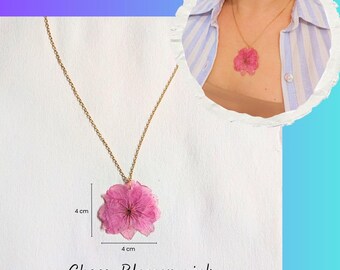 Può includere: Una collana a catena color oro con un ciondolo a forma di fiore di ciliegio rosa. Il ciondolo misura 4 cm per 4 cm, come indicato dal testo e dalle linee di misurazione. Il testo "Cherry Blossom pink" è stampato sotto il ciondolo.