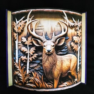 May include: A 3D pop-up book art piece depicting a deer standing in a forest setting. The deer is brown with large antlers and is surrounded by trees and foliage. The book is made of paper and is folded to create the 3D effect.