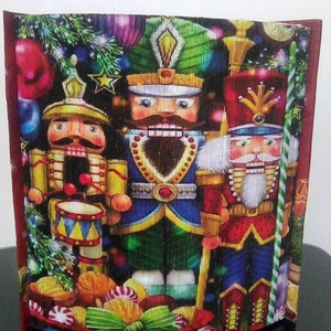 May include: Three nutcracker figurines stand in front of a Christmas tree with ornaments and candy canes. The nutcrackers are dressed in traditional costumes with red, blue, and green accents. The nutcrackers are holding instruments and a candy cane.