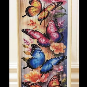 Op de afbeelding: Decoratieve boeksculptuur met een kleurrijk vlinderontwerp. Het kunstwerk toont kleurrijke vlinders in blauw, oranje en roze tinten tegen een bloemenachtergrond. De pagina's van het boek zijn ingewikkeld gevouwen.