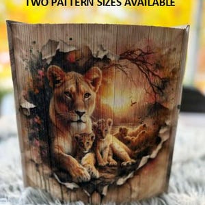 May include: A wooden wall art piece with a torn paper effect revealing a painting of a lioness and her cubs in a sunset scene. The lioness is brown with a light brown mane and her cubs are light brown.