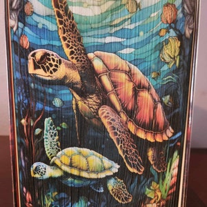 May include: A book art sculpture of a sea turtle swimming in an underwater scene. The sculpture is made of folded pages of a book, creating a 3D effect. The turtle is brown and orange with a green shell. The background is blue and green with coral and other sea life.