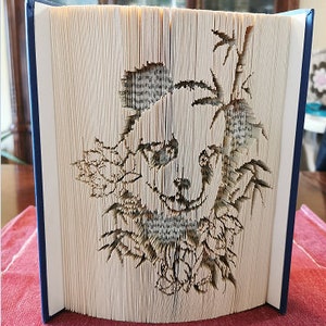 Peut inclure: Une sculpture d'art de livre représentant un panda entouré de bambou. Le panda est réalisé à partir des pages d'un livre qui ont été découpées et pliées pour créer un effet 3D.