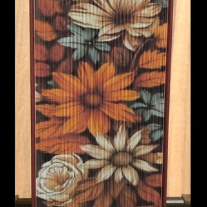 May include: A brown book with a floral design on the cover. The flowers are in shades of orange, yellow, white, and blue. The book is bound with a brown spine.