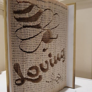 May include: A book with pages folded and cut to create a three-dimensional design of the word "love".