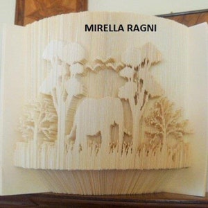 Può includere: Una scultura di arte di libro piegato che rappresenta un elefante in piedi in una foresta. La scultura è realizzata in carta ed è di colore marrone chiaro. Il titolo "Mirella Ragni" è stampato sulla parte anteriore della scultura.