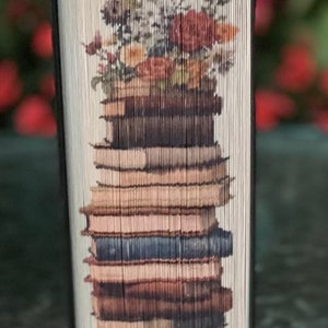 May include: A stack of books with a floral design on the cover. The books are arranged in a tower, with the largest book at the bottom and the smallest book at the top. The floral design is a bouquet of flowers in shades of pink, red, and white.