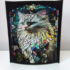 Può includere: Un gatto bianco con gli occhi azzurri è raffigurato in stile vetrata. La pelliccia del gatto è resa in un mosaico di pezzi di vetro colorati, creando un design vibrante e intricato.
