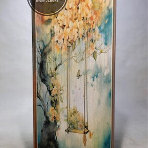 Pode incluir: Uma pintura em aquarela de uma árvore com flores brancas e um balanço pendurado em seus galhos. O fundo é um suave lavado de aquarela azul e branco. O texto "CRAFTED BY BRIGHT SIDE STUDIO PATTERN BY BVDM DESIGNS" está impresso no canto superior esquerdo.