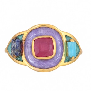 以下が含まれることがあります： 中央に正方形のルビーを配し、ラベンダーエナメルの正方形で囲まれたゴールドトーンのリング。リングの両側にターコイズとラピスラズリのアクセント。ユニークで芸術的なデザイン。