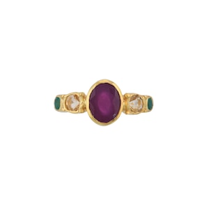May include: A gold ring with a large oval ruby gemstone surrounded by smaller white and green gemstones.