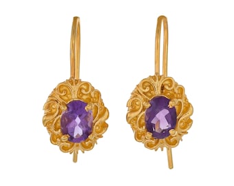 May include: A pair of gold earrings with a purple amethyst gemstone in each. The earrings have a detailed, ornate design.