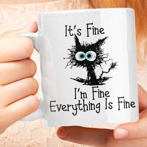 May include: White ceramic mug featuring a black and white cartoon cat with the text "It's Fine I'm Fine Everything Is Fine"