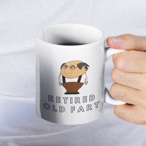 K&ouml;nnte beinhalten: Wei&szlig;e Keramik-Tasse mit einer Cartoon-Illustration eines Mannes mit Brille und dem Text "RETIRED OLD FART". Die Illustration zeigt den Mann in einem wei&szlig;en Hemd, brauner Hose und Hosentr&auml;gern. Die Tasse hat einen wei&szlig;en Henkel.