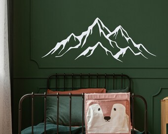May include: A black metal bed frame with a pink and white storage organizer hanging on the side. The bed has a green throw blanket and a white mountain decal on the wall behind it.