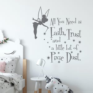Könnte beinhalten: Ein weißes Kinderzimmer mit Bett, Beistelltisch und einem Einhorn-Stofftier. An der Wand befindet sich eine graue Fee-Silhouette und der Text "All You Need is Faith, Trust and a little bit of Pixie Dust."