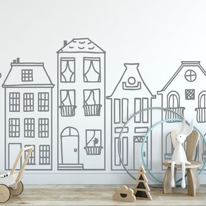 May include: A white wall with a gray outline of a row of houses. The houses have windows, doors, and roofs. There are toys in front of the wall, including a white doll stroller, a wooden rabbit, and a wooden hoop.