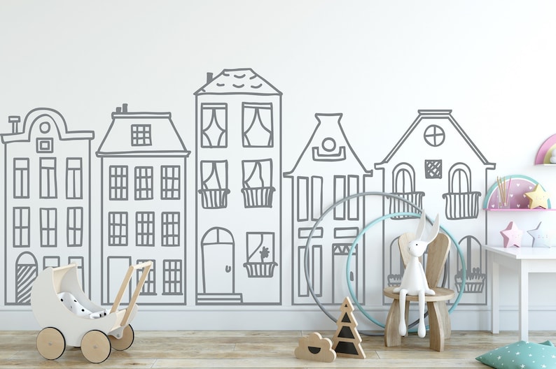 May include: A white wall with a gray outline of a row of houses. The houses have windows, doors, and roofs. There are toys in front of the wall, including a white doll stroller, a wooden rabbit, and a wooden hoop.