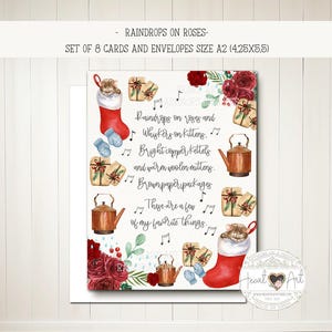 May include: A set of 8 cards and envelopes, size A2 (4.25x5.5 inches), featuring a watercolor design. The design includes a red stocking with a cat, copper kettles, wrapped gifts, and the text "Raindrops on roses and Whiskers on kittens."