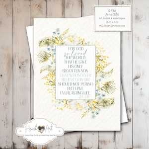 May include: A white A2 card with a floral wreath design in yellow, blue, and green. The card features the text "For God so loved the world..." from John 3:16. Includes a smaller card with product details.
