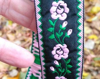 Puede incluir: Borde floral rosa y verde sobre fondo negro. El borde presenta un patrón repetido de rosas rosas y hojas verdes.