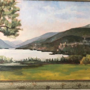 Puede incluir: Una pintura de una escena de lago con un gran árbol en primer plano y montañas en el fondo. El lago es de color azul claro y las montañas son de color verde oscuro. El cielo es de color azul claro con algunas nubes blancas.