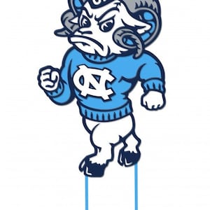 Peut inclure: Une mascotte de b&eacute;lier de dessin anim&eacute; portant un pull bleu avec un logo "UNC" blanc et un chapeau bleu et blanc avec "UNC" dessus. Le b&eacute;lier est debout sur deux poteaux bleus.