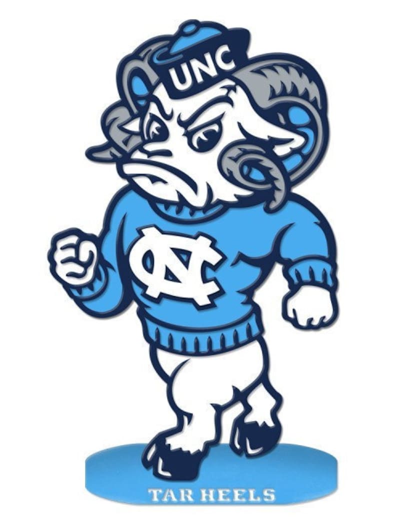 Peut inclure: Une mascotte de b&eacute;lier de dessin anim&eacute; bleue et blanche portant un chapeau bleu avec les lettres "UNC" dessus. Le b&eacute;lier porte un pull bleu avec un logo "UNC" blanc. Le b&eacute;lier se tient sur une base bleue avec les mots "TAR HEELS" &eacute;crits dessus.