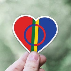 May include: A heart-shaped sticker with the flag of the Sámi people. The flag is red, blue, yellow, and green with a circle in the center.