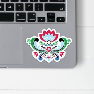 May include: A colorful sticker with a stylized floral design. The design features red, blue, green, and white flowers with black outlines.