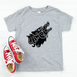 May include: A heather gray short-sleeve t-shirt featuring a black graphic of a howling wolf head with intricate swirling patterns. The design is centered on the chest. A pair of red low-top canvas sneakers with white laces and white rubber soles.