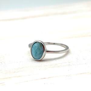 May include: A silver ring with a light blue oval-shaped gemstone.
