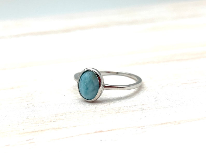 May include: A silver ring with a light blue oval-shaped gemstone.
