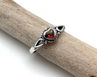 May include: A silver ring with a heart-shaped opal gemstone. The ring has a delicate design with small details around the stone.