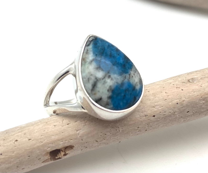Peut inclure: Une bague en argent avec une pierre pr&eacute;cieuse bleu et blanc en forme de larme.
