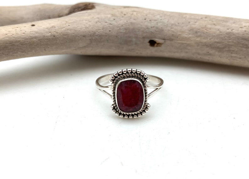 Op de afbeelding: Een zilveren ring met een rode edelsteen in een geperde zetting.