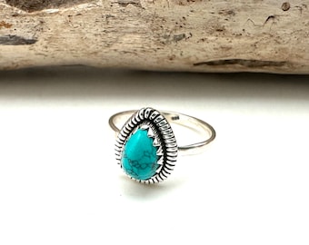 May include: A silver ring with a turquoise gemstone set in a teardrop shape. The ring has a decorative band with a braided design.