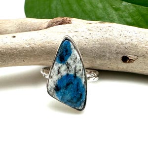 May include: A silver ring with a blue and white stone. The stone is a triangular shape and has a unique pattern.