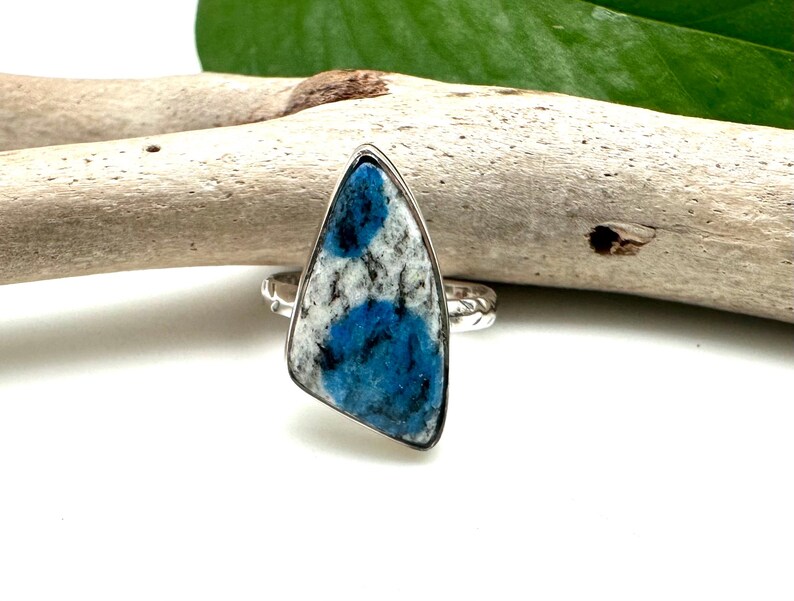 May include: A silver ring with a blue and white stone. The stone is a triangular shape and has a unique pattern.