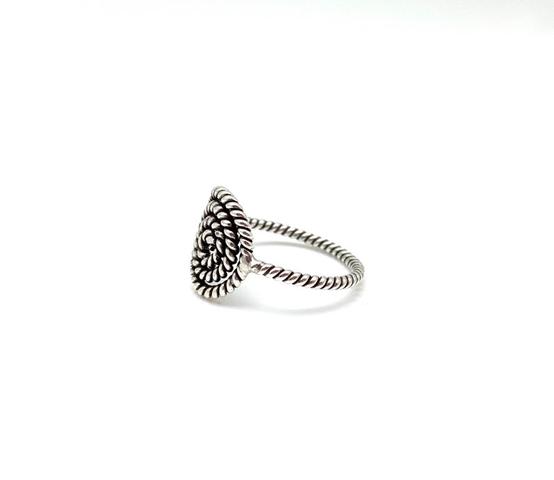 May include: A silver ring with a spiral design on the top. The band is twisted.