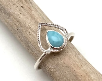 May include: A silver ring with a teardrop-shaped blue gemstone set in a heart-shaped frame.