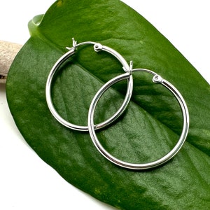 May include: A pair of silver hoop earrings. The earrings are simple and elegant, and they would be a great addition to any jewelry collection.