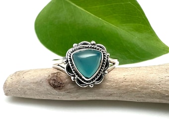 May include: A silver ring with a triangular blue-green gemstone set in a decorative silver setting.