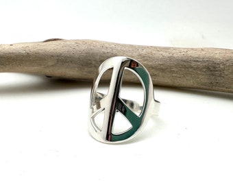 May include: A silver peace sign ring. The ring is made of a smooth, shiny metal and has a simple, classic design.
