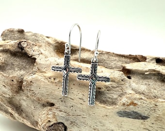 May include: Silver cross earrings with a detailed design. The cross is silver with a black finish and has a diamond-shaped design in the centre.