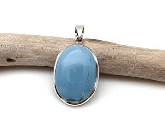 May include: A silver pendant with a light blue oval opal gemstone. The pendant is on a piece of driftwood.