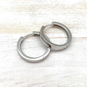 May include: A pair of silver hoop earrings. The earrings are simple and elegant, and they would be a great addition to any jewelry collection.