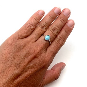 May include: A silver ring with a light blue oval gemstone.
